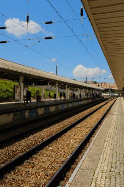 Portekiz 'in Lizbon bölgesindeki uzun platformlu ve mavi gökyüzü perspektifli banliyö tren rayları. Yüksek kalite fotoğraf
