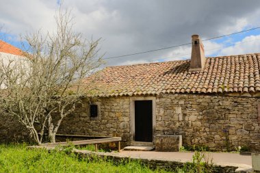 Portekiz 'in kırsal kesimindeki Fatima Portekiz köyünde kil kil kiremit çatı bacası ve yapraksız çayırı olan geleneksel taş kulübe. Yüksek kalite fotoğraf