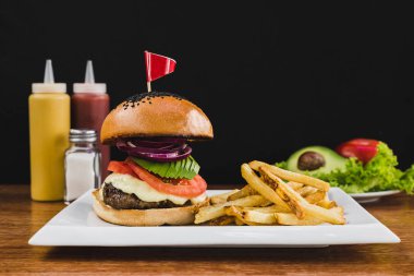 Burger avokado, domates, soğan, peynir ve patates kızartması ile