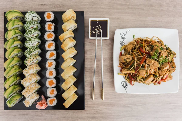 Suşi yakisoba ve soya sosu ile ahşap bir masa üzerinde rulo