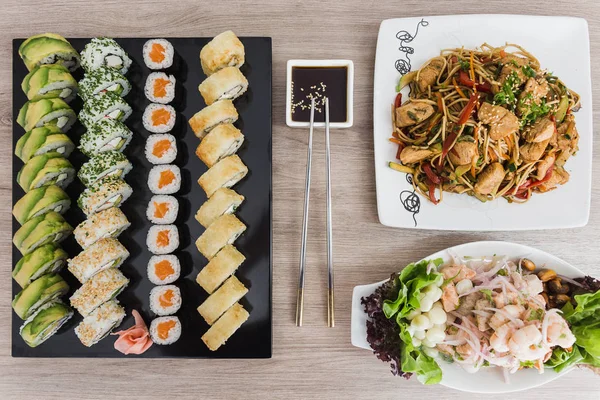 Suşi yakisoba, ceviche ve soya sosu ile ahşap bir masa üzerinde rulo