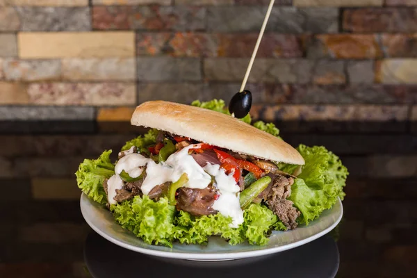 Sándwich de carne con lechuga, cebolla, champiñones, pimienta y mayonesa con fondo de pared de ladrillo — Foto de Stock