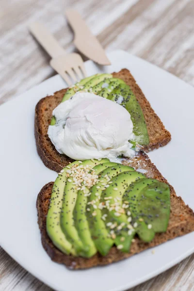 Ahşap bir masada avokado ve yumurta ile iki tost