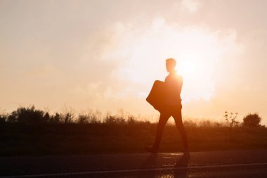 Bavul, el günbatımında yürüyen genç hipster adam