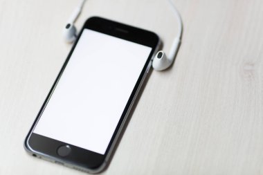 Mockup ekran ve iki tarafta kulaklık ile Smartphone. Ahşap masa arka plan