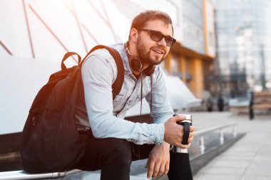 Modern gülümseyerek el Siyah sırt, boyun ve termo kupa kahve ile kulaklık ile hippi sakallı