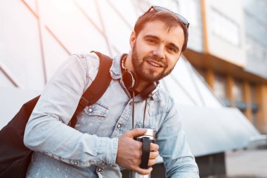 Modern gülümseyerek el Siyah sırt, boyun ve termo kupa kahve ile kulaklık ile hippi sakallı