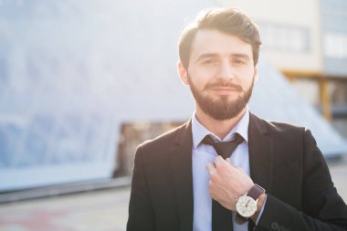Takım elbise giymiş sakallı hippi işadamı portresi kravatını düzeltiyor