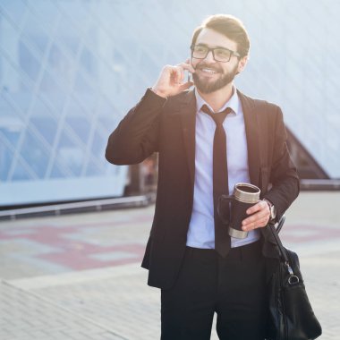 Kahve ve güneş ışığı ile office yapı zemin üzerine elinde smartphone ile başarılı ve genç işadamı