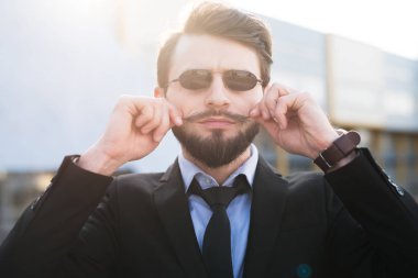 Takım elbise giymiş güneş gözlüklü sakallı hippi portresi.