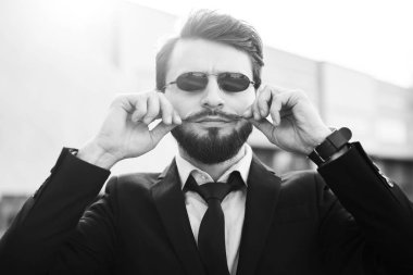 Takım elbise giymiş güneş gözlüklü sakallı hippi portresi.