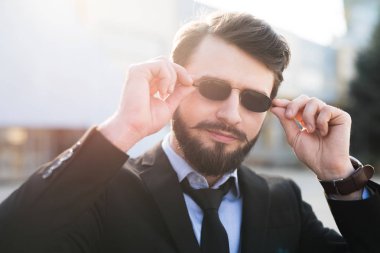Takım elbise giymiş güneş gözlüklü sakallı hippi portresi.