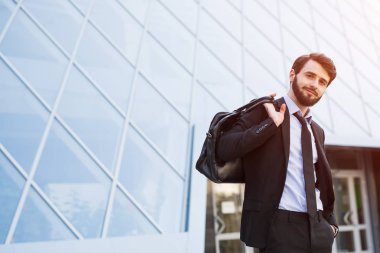 Gökdelen arka plan üzerinde çanta ile modern iş adamı.