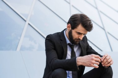 Üzgün sakallı işadamı yazıhane kurmak yanında takım elbiseli.