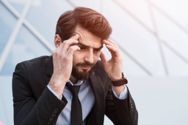 Üzgün sakallı işadamı yazıhane kurmak yanında takım elbiseli.