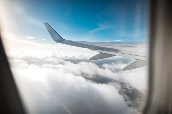 Wing of an airplane above the clouds, background of a blue sky. — Stock Photo, Image