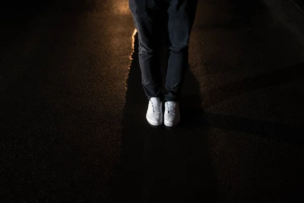 Benen van de man in water op asfalt in de nacht. — Stockfoto