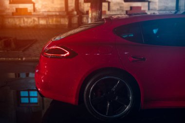 Kırmızı modern spor araba, gece şehirde yağmur sonra arkadan görünüm.
