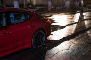 Kırmızı modern spor araba, gece şehirde yağmur sonra arkadan görünüm.