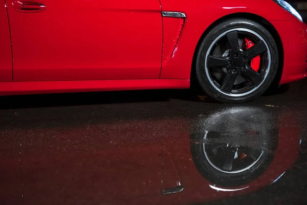 Gros plan de la voiture de sport moderne rouge, après la pluie dans la ville de nuit . — Photo
