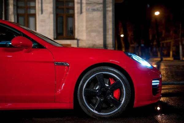 Close-up de carro esporte moderno vermelho, após a chuva na cidade noturna . — Fotografia de Stock