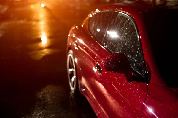 Visão traseira do carro esporte moderno vermelho, após a chuva na cidade noturna . — Fotografia de Stock
