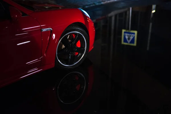 Gros plan de la voiture de sport moderne rouge, après la pluie dans la ville de nuit . — Photo