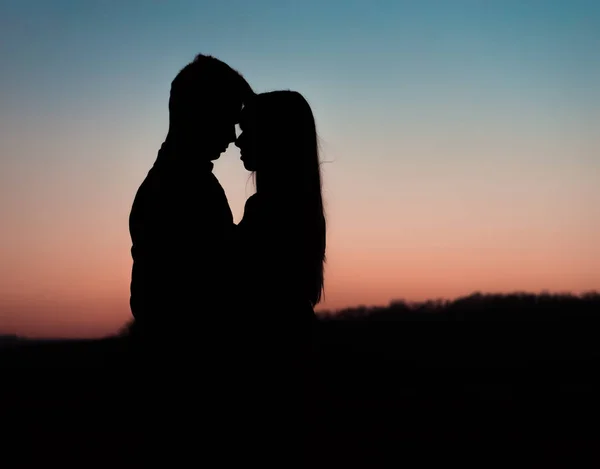 Silhouette de jeune couple sur fond de coucher de soleil . — Photo