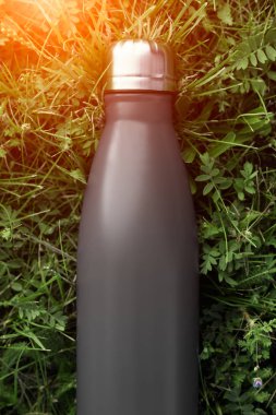 Paslanmaz Termos şişe su, siyah renk için. Güneş ışığı etkisi yeşil çim zemin üzerine izole