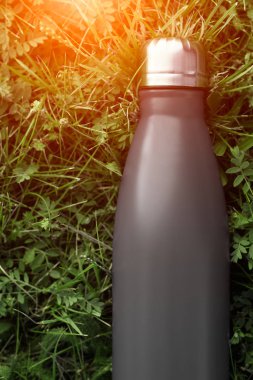Paslanmaz Termos şişe su, siyah renk için. Güneş ışığı etkisi yeşil çim zemin üzerine izole