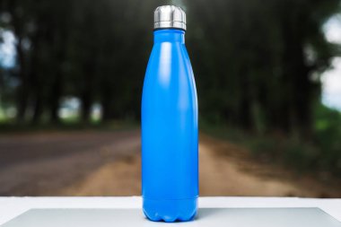 Paslanmaz termos su şişe beyaz masada açık. Mavi renk