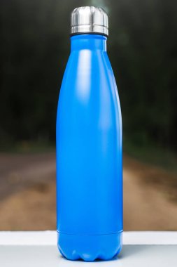 Paslanmaz termos su şişe beyaz masada açık. Mavi renk