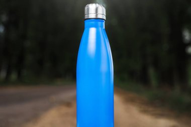 Paslanmaz termos su şişe beyaz masada açık. Mavi renk