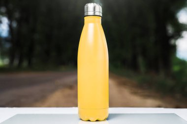 Paslanmaz termos su şişe beyaz masada açık. Sarı renk