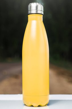 Paslanmaz termos su şişe beyaz masada açık. Sarı renk