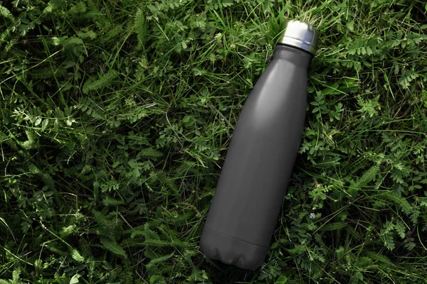 不锈钢热水瓶隔离在户外的绿草上 黑色哑光颜色 没有效果的水平照片 — 图库照片