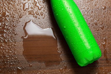 Paslanmaz çelik termos ahşap bir masaya izole şişe su ile püskürtülür. Açık yeşil renk