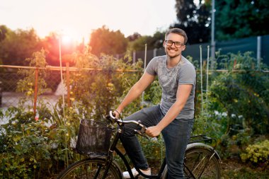 Bisiklet Park ile mutlu genç adam. Gün batımında görüş ile gözlük