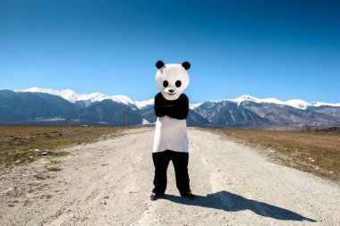 Panda elbiseli bir adam bir arka plan Dağları'nın boş bir yolda bekliyor