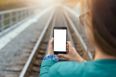 Mock up of woman with smartphone in hands on train railroad