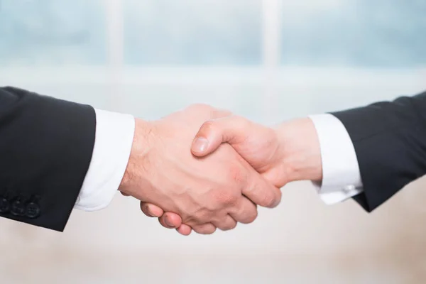 Handshake of two people, businessmen on a light background