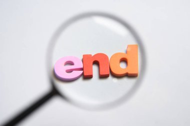 Sonunda, büyüteç altında renkli harflerle beyaz arka plan üzerinde yazılı kelime