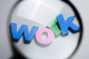 Büyüteç altında renkli harflerle beyaz arka plan üzerinde yazılı iş, kelime