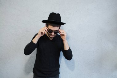 Hipster adam portresi beyaz arka plan üzerinde güneş gözlüğü elinde şapka ile Siyah giyimli