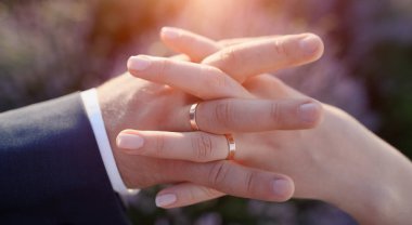 Düğün çift elle lavanta çiçek alan ve günbatımı arka plan üzerinde nişan yüzük