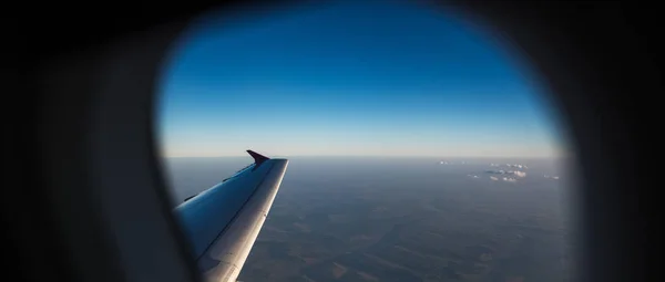 Vista del ala del avión a través de la ventana. Volando sobre la tierra . —  Fotos de Stock