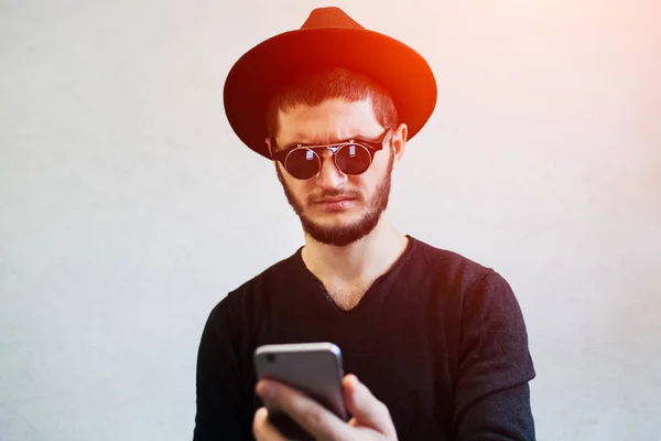 Portrait of sad young man looking shocked at smartphone.