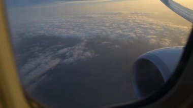 Uçak kanadı uçak penceresinden görünümü. Gündoğumu, bulutların üzerinde uçan.