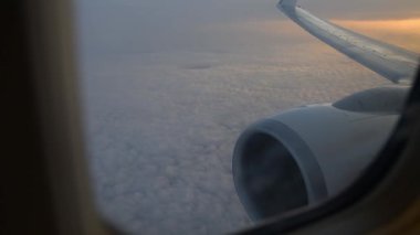 Uçak kanadı uçak penceresinden görünümü. Gündoğumu, bulutların üzerinde uçan.