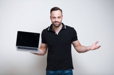 Laptop ile beyaz arka plan üzerinde tutan genç gülümseyen adam